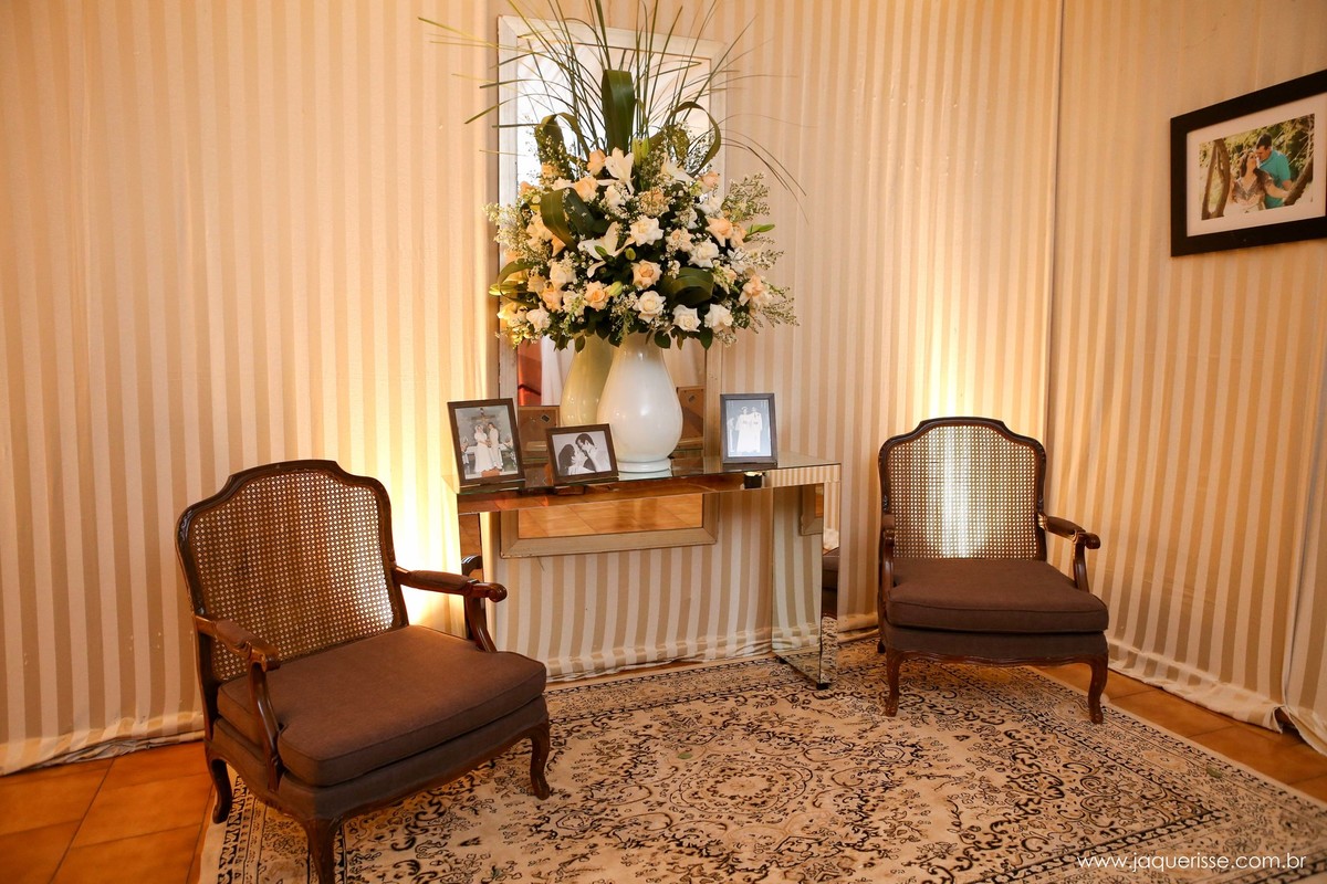parte da decoração que mostra aparador em espelho com um lindo vaso com flores e porta retratos com uma cadeira de cada lado no click da fotógrafa de casamento Bebedouro SP Jaque Risse