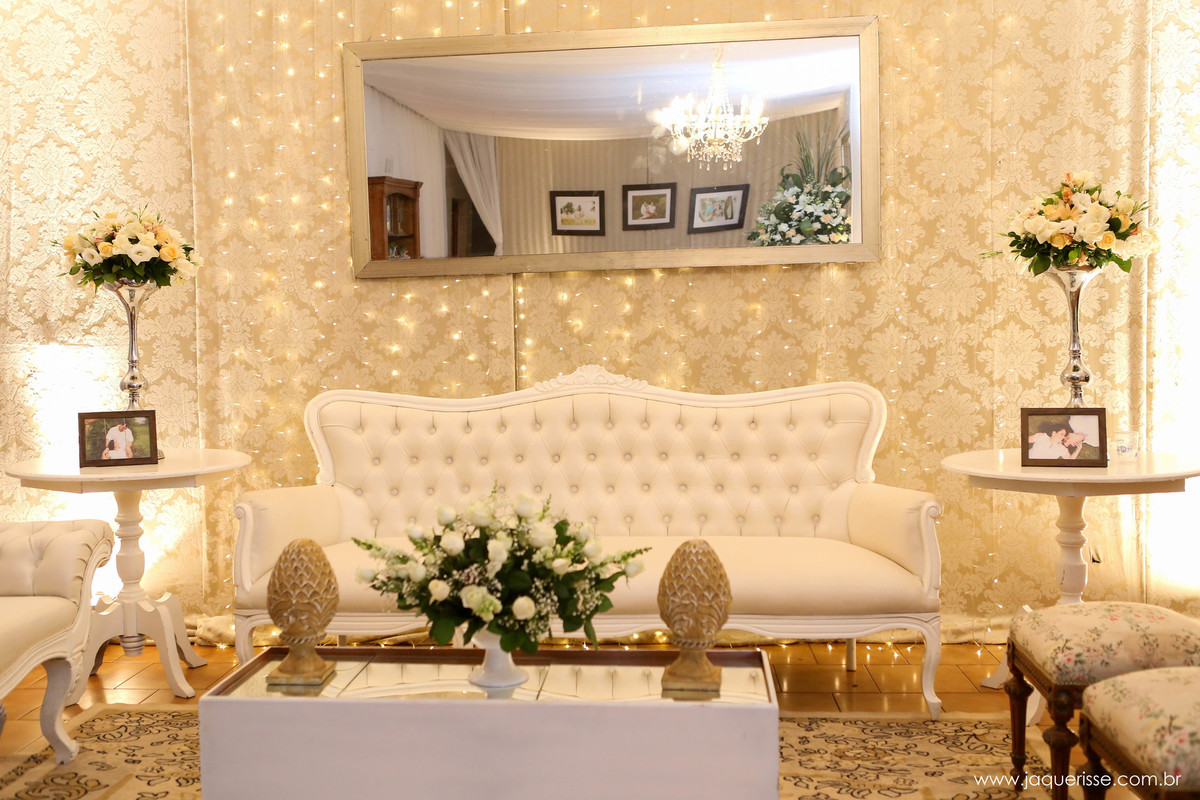 parte da decoração que mostra um lindo sofá branco com uma parede adamascada  e com luzes ao fundo no click da fotógrafa de casamento Bebedouro SP Jaque Risse