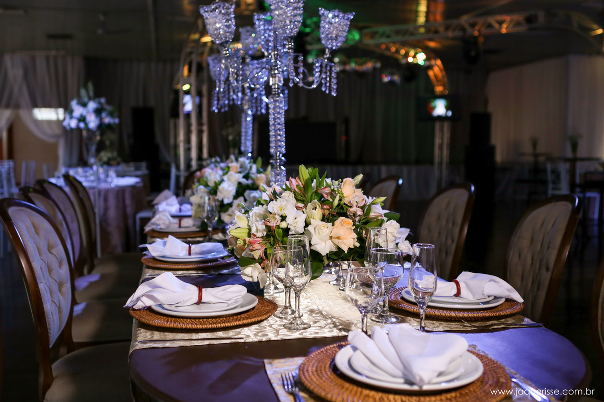 parte da decoração que mostra os pratos nas mesas com um arranjo floral ao centro e um castiçal  no click da fotógrafa de casamento Bebedouro SP Jaque Risse