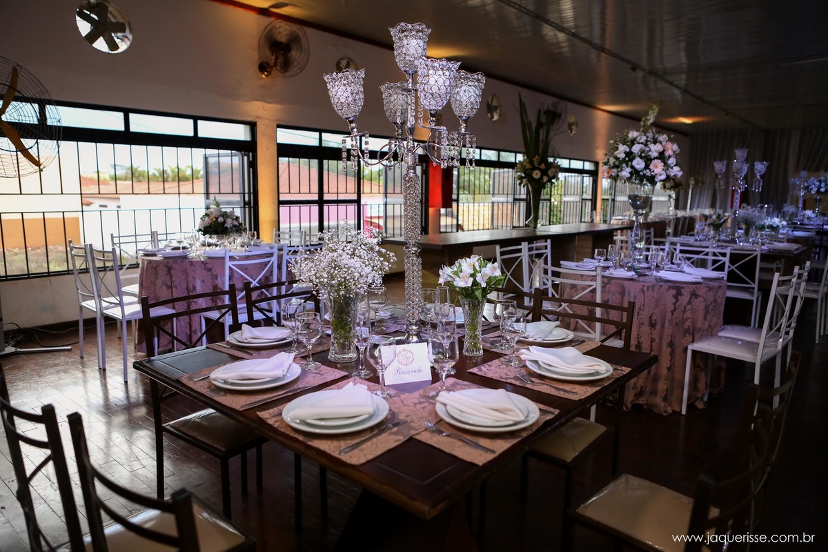 parte da decoração que mostra os pratos nas mesas com um arranjo floral ao centro e um castiçal  no click da fotógrafa de casamento Bebedouro SP Jaque Risse