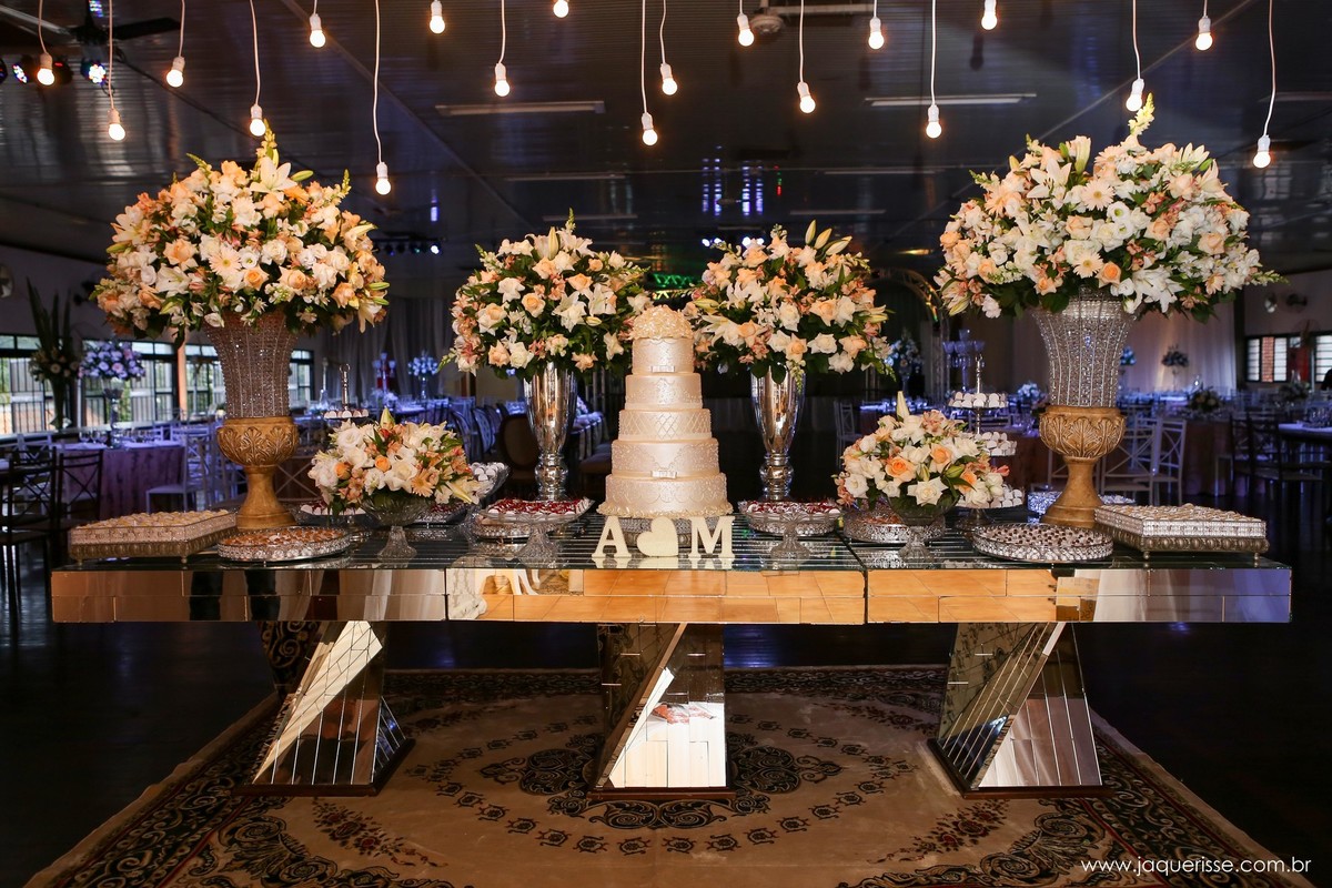 mesa do bolo decorada com seis arranjos florais o bolo ao centro com as iniciais A e M no click da fotógrafa de casamento Bebedouro SP Jaque Risse