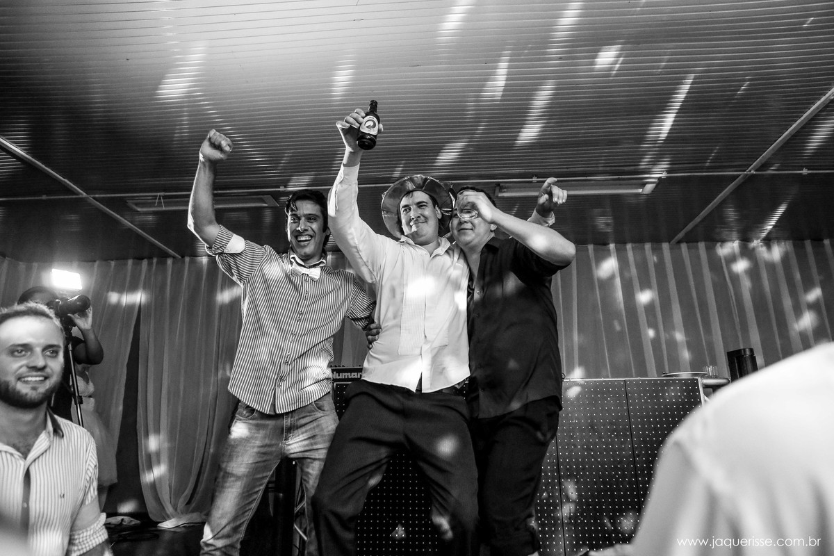 noivo abraçado com dois amigos dançando em cima do palco no click da fotógrafa de casamento Bebedouro SP Jaque Risse