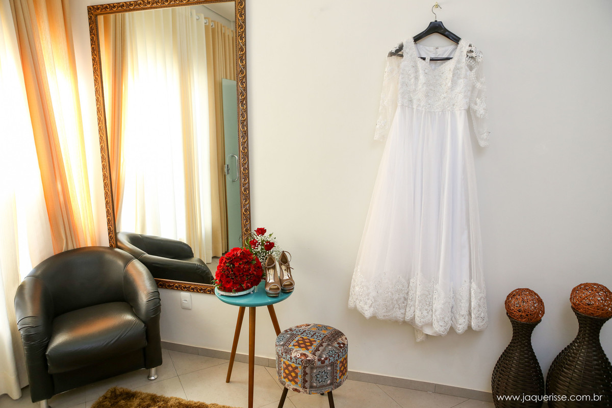 vestido pendurado no cabide na parede do salão de beleza com os sapatos e o bouquet sobre uma mesinha no click da fotógrafa de casamento Bebedouro SP Jaque Risse