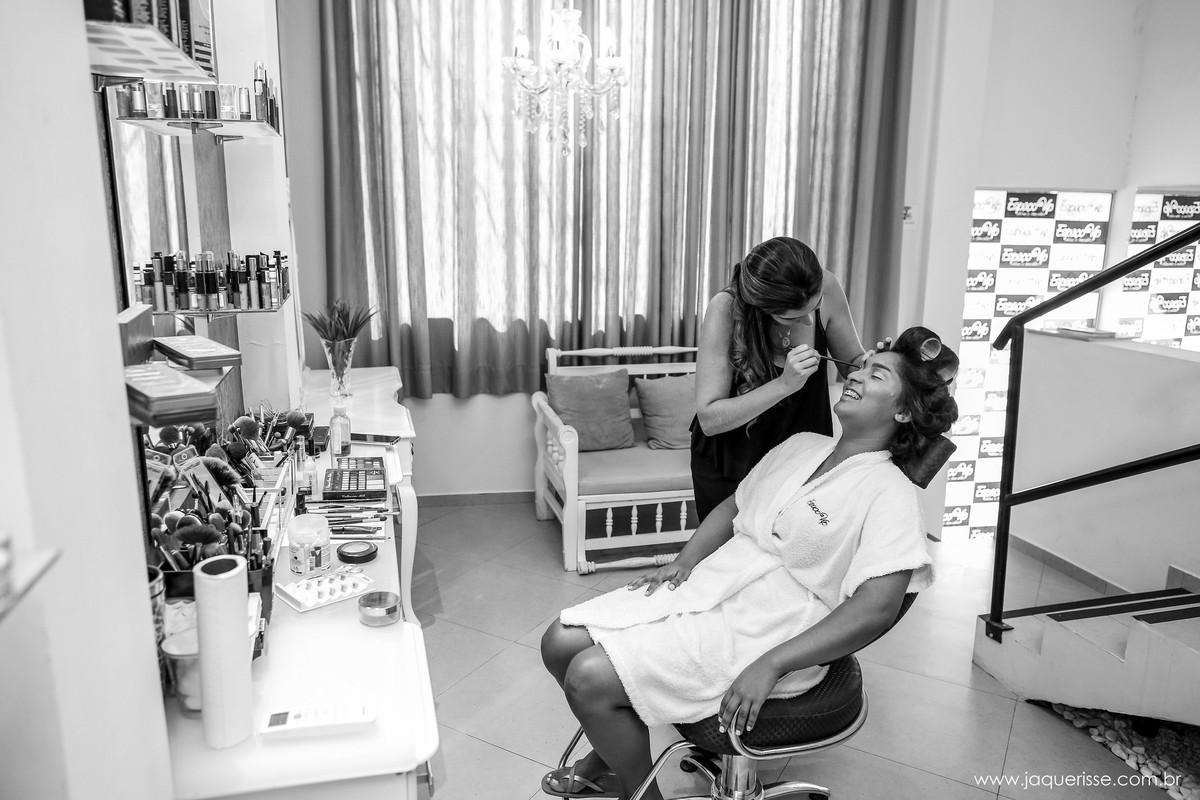 vista do salão de beleza com a maquiadora fazendo a maquiagem da noiva que esta sentada na cadeira no click da fotógrafa de casamento Bebedouro SP Jaque Risse