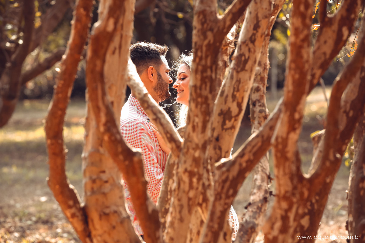 Casal de noivos em um momento romântico se abraçando um de frente para o outro por entre as arvores na cena do Pre wedding clicado pela fotografo de casamento jaque risse em bebedouro sp