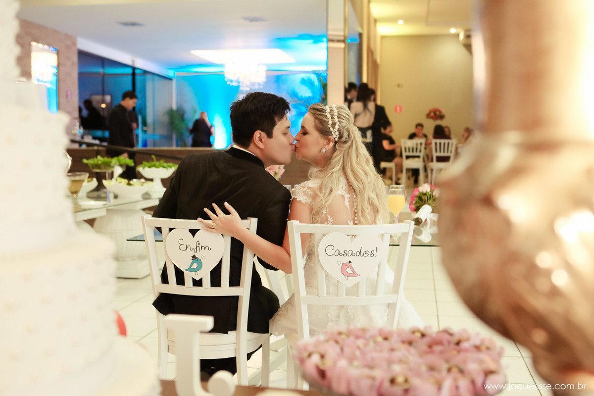 jaque risse, andre risse, estudio bebedouro, melhores fotografos, noivos sentados em sua mesa e dando um beijunho