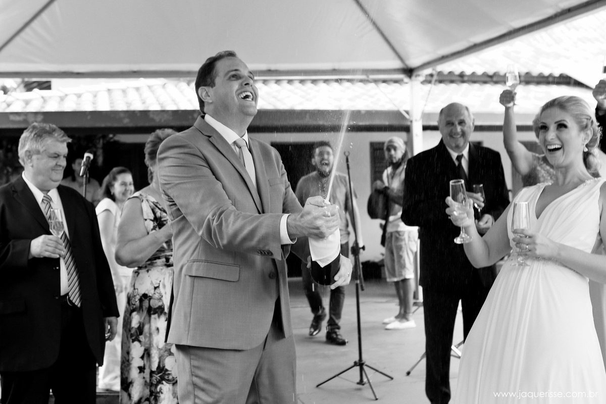 jaque risse, andre risse, estudio bebedouro, melhores fotografos, noivo sorrindo abrindo a espumante, noiva com as taças nas maos, padrinhos em volta