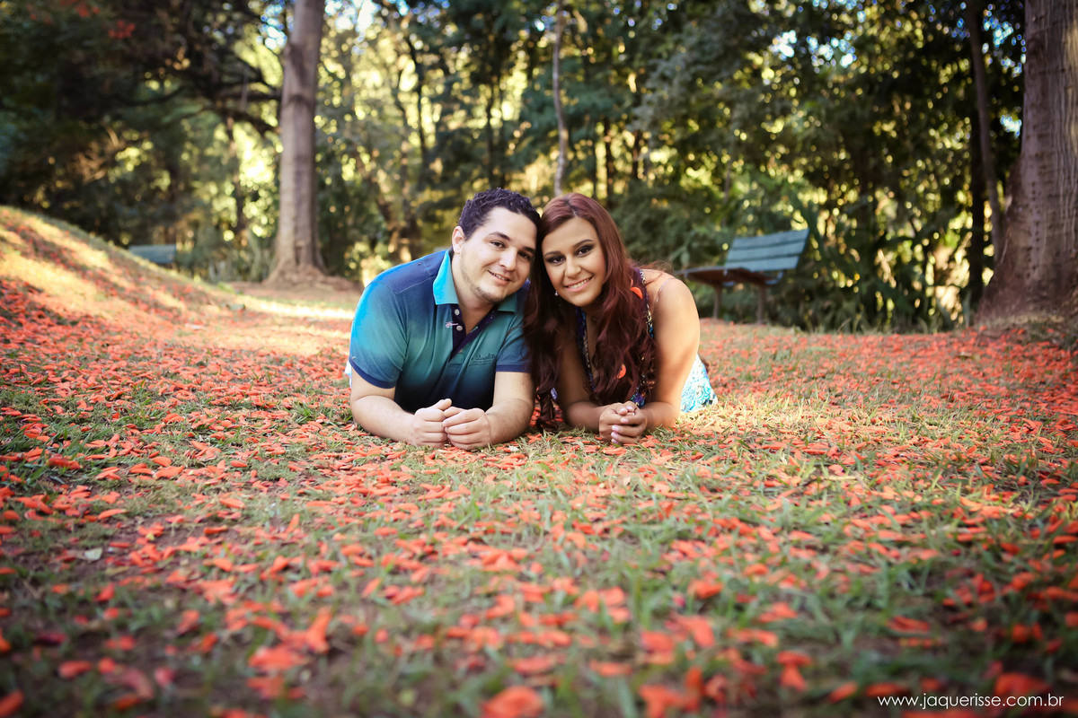 jaque risse, andre risse, estudio bebedouro, melhores fotografos, noivos apoiados no chao, olhando para frente e sorrindo, um banco de madeira no fundo, varias arvores