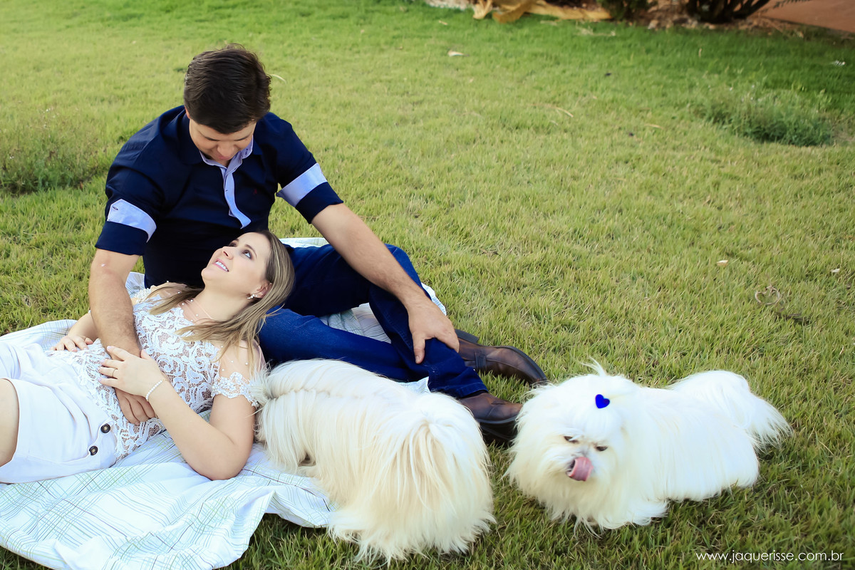 jaque risse, andre risse, estudio bebedouro, melhores fotografos, noivo sentado na grama, noiva deitada em seu colo, ambos se olhando, e os cachorros deitados ao lado