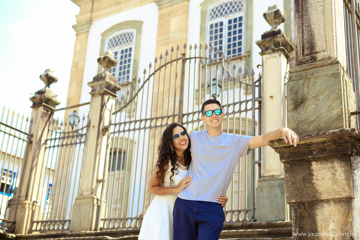 jaque risse, andre risse, estudio bebedouro, melhores fotografos, noivo apoiado no pilar, noiva abraçando ele de lado, ambos de oculos de sol e sorrindo