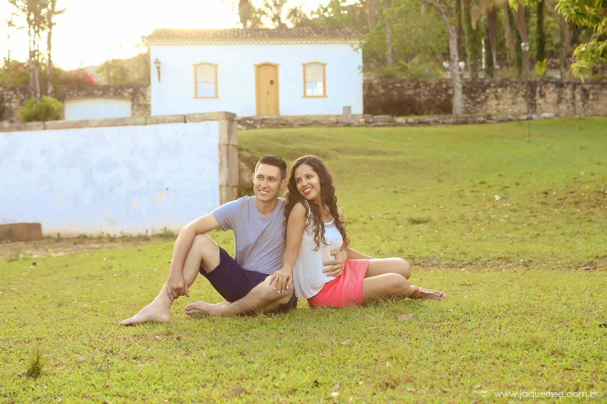 jaque risse, andre risse, estudio bebedouro, melhores fotografos, noivos sentados na grama, olhando para o lado e sorrindo, e uma casinha de fundo