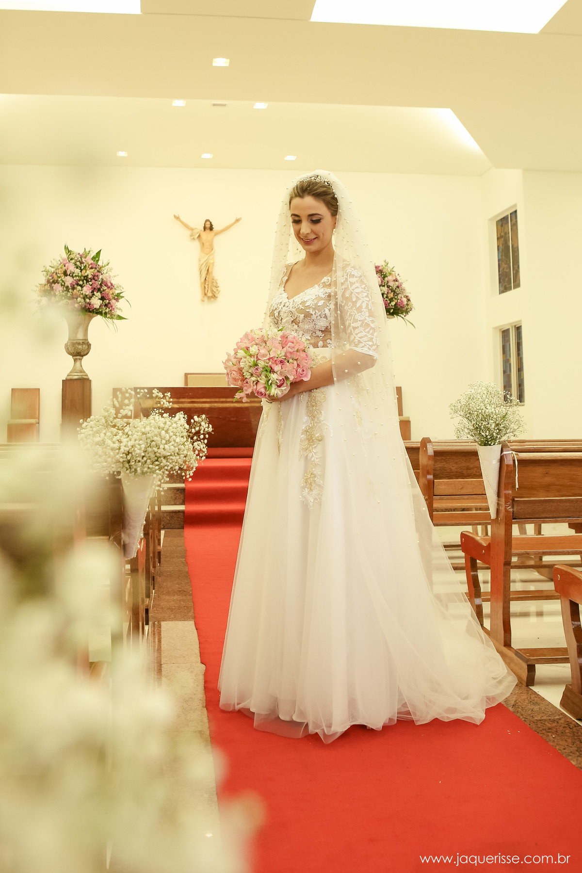 jaque risse, andre risse, estudio bebedouro, melhores fotografos, noiva no meio da igreja olhando seu buque e sorrindo, decoracao ao redor dos bancos
