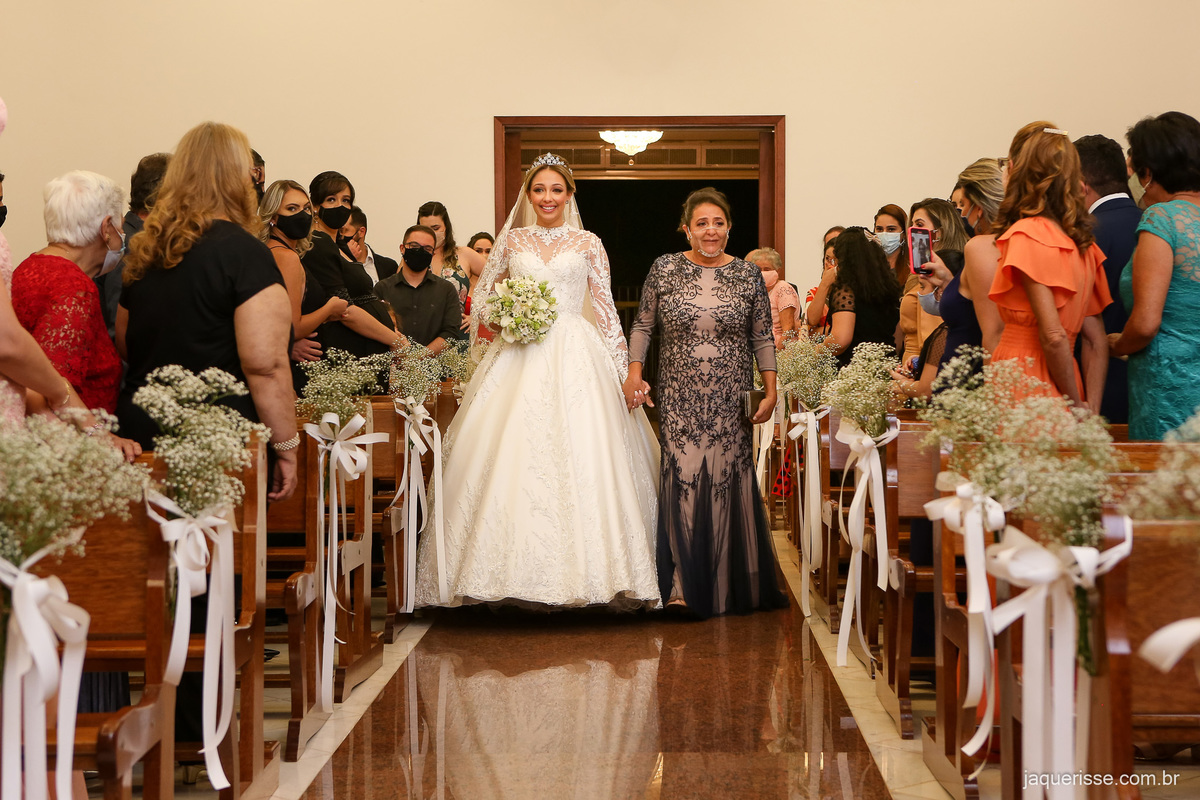 noiva entrando pelo corredor da igreja junto com sua mãe fotografado pela jaque risse em bebedouro sp