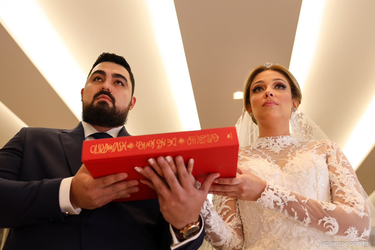 noivo e noiva segurando a bíblia durante o sermão do celebrante do casamento registrado pela jaque risse em bebedouro sp 