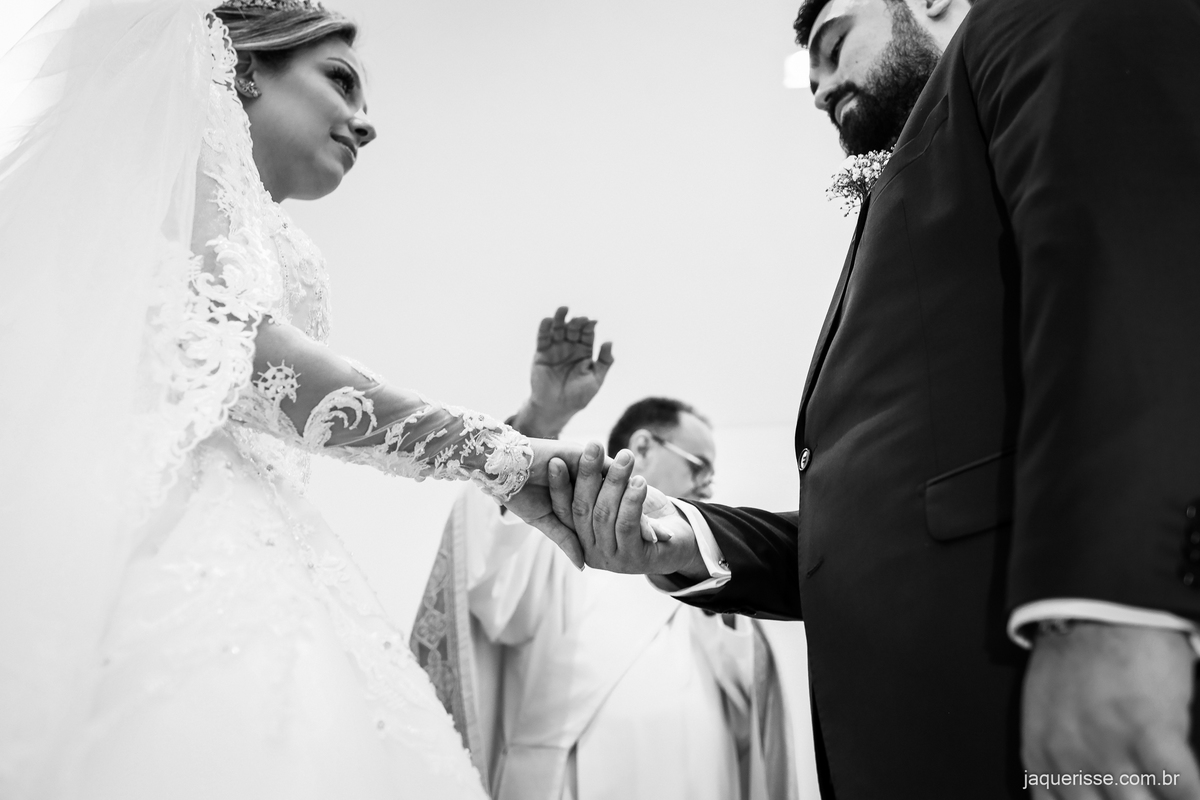 padre abençoando as mão dos noivos com as recém colocadas alianças fotografado pela jaque risse em bebedouro sp