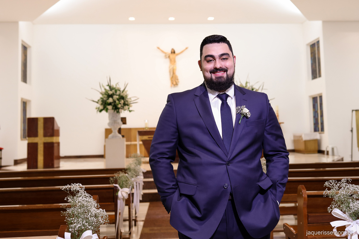 noivo posando para um retrato bem ao centro do corredor da igreja vazia fotografado pela jaque risse em bebedouro sp