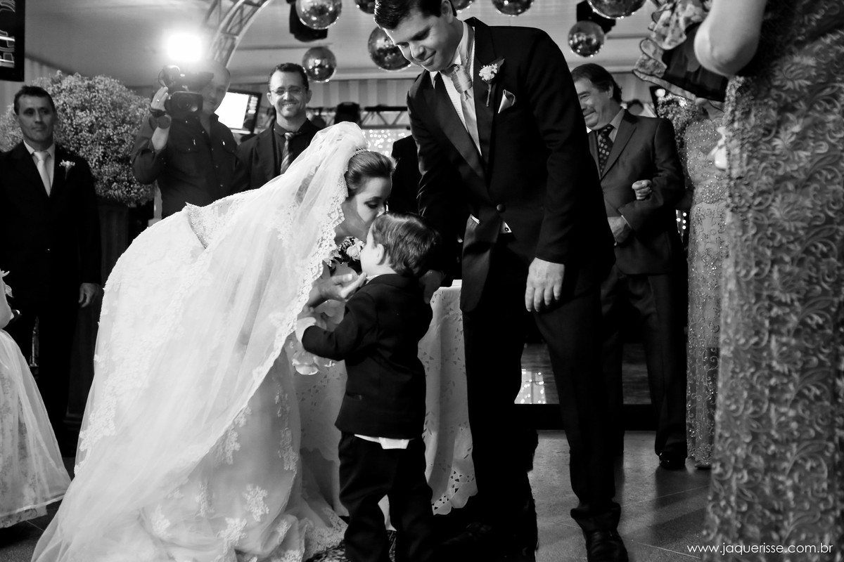 jaque risse, andre risse, estudio bebedouro, melhores fotografos, noiva beijando a testa de seu filho, o veu caindo em seu ombro,noivo ao lado olhando , e os convidados atras na pista de dança