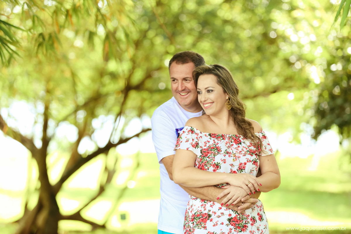 jaque risse, andre risse, estudio bebedouro, melhores fotografos, noivo abraçando a noiva por traz, os dois olhando para o lado e sorrindo, dia ensolarado e um lugar