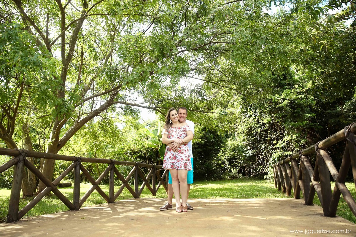 jaque risse, andre risse, estudio bebedouro, melhores fotografos, noivo abraçando a noiva por traz, arvores atraz e uma cerca de madeira, ambos sorrindo