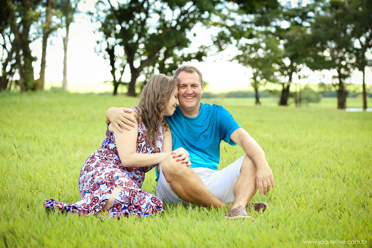 jaque risse, andre risse, estudio bebedouro, melhores fotografos, ambos sentados na grama noico sorrindo com pernas cruzadas, noiva apoiando as maos e rosto no noivo
