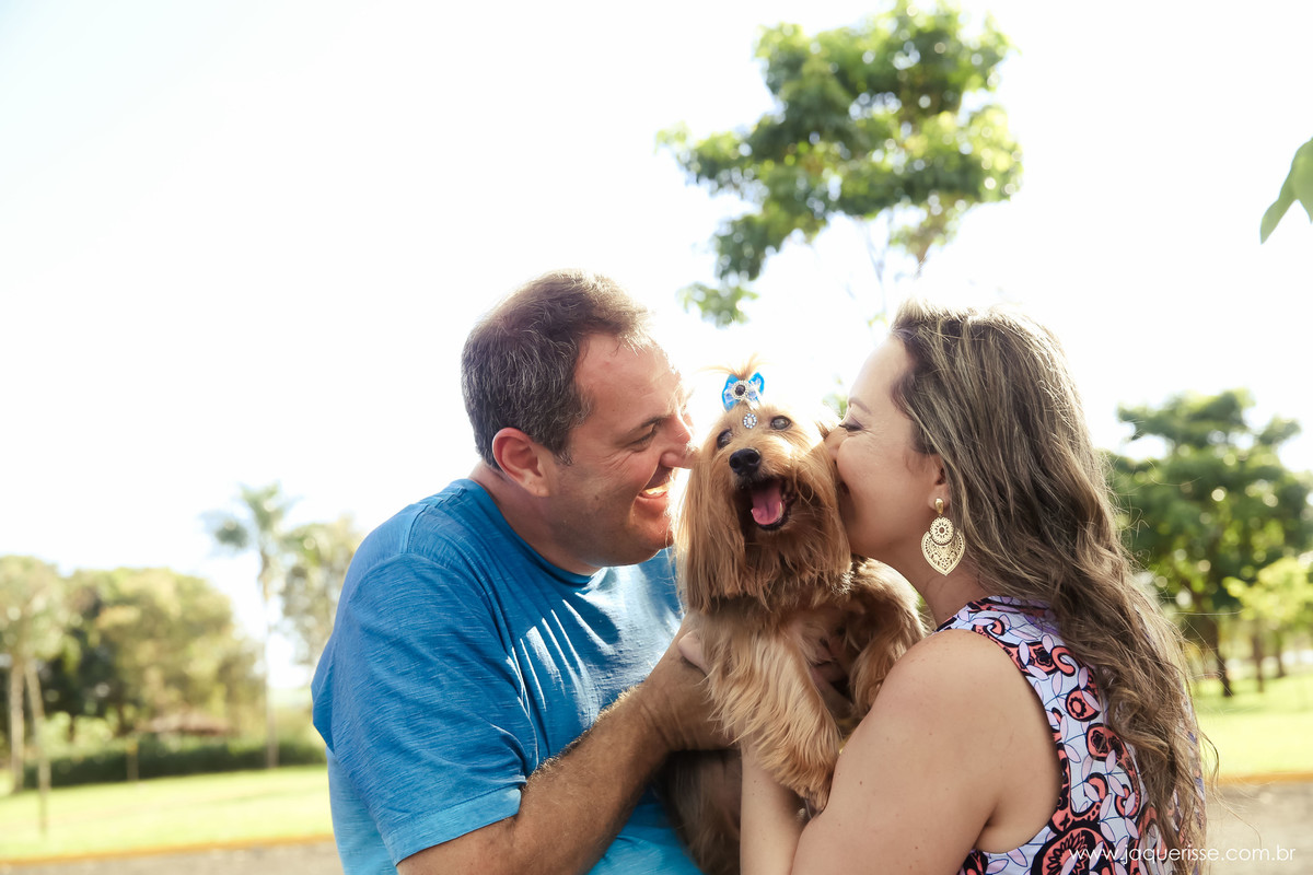 jaque risse, andre risse, estudio bebedouro, melhores fotografos, a noiva beijando o cachorro e o noivo sorrindo para o cachorro e uma arvore de fundo