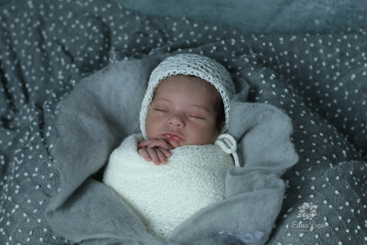 foto de bebe no wrap branco com toquinha branca em manta azul durante ensaio realizado em sao bernardo do campo