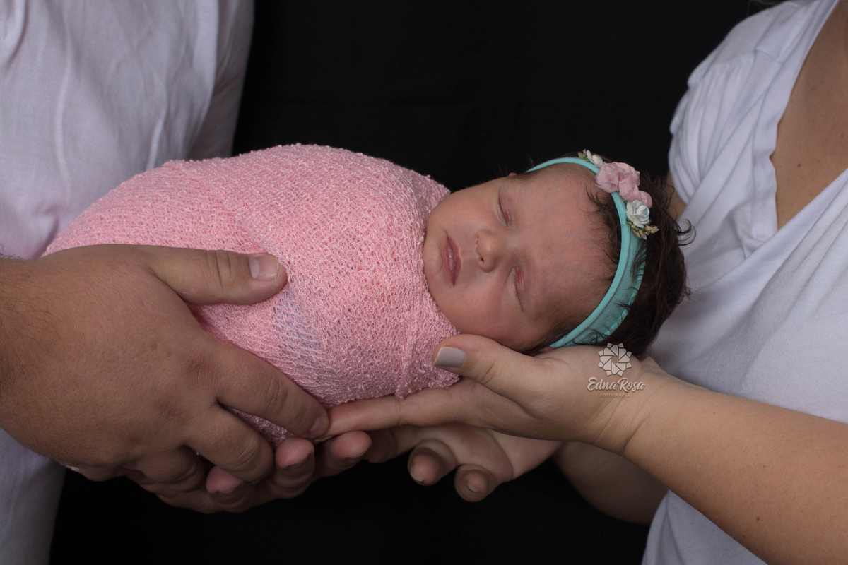 papai e mamae segurando bebe enrolado no wrap rosa durante ensaio em sao bernardo do campo