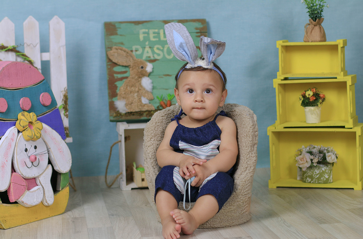 Fotos do tema páscoa no estúdio Edna Rosa Fotografia. Bebê usando orelhinha de coelhinho e segurando ovo colorido.
