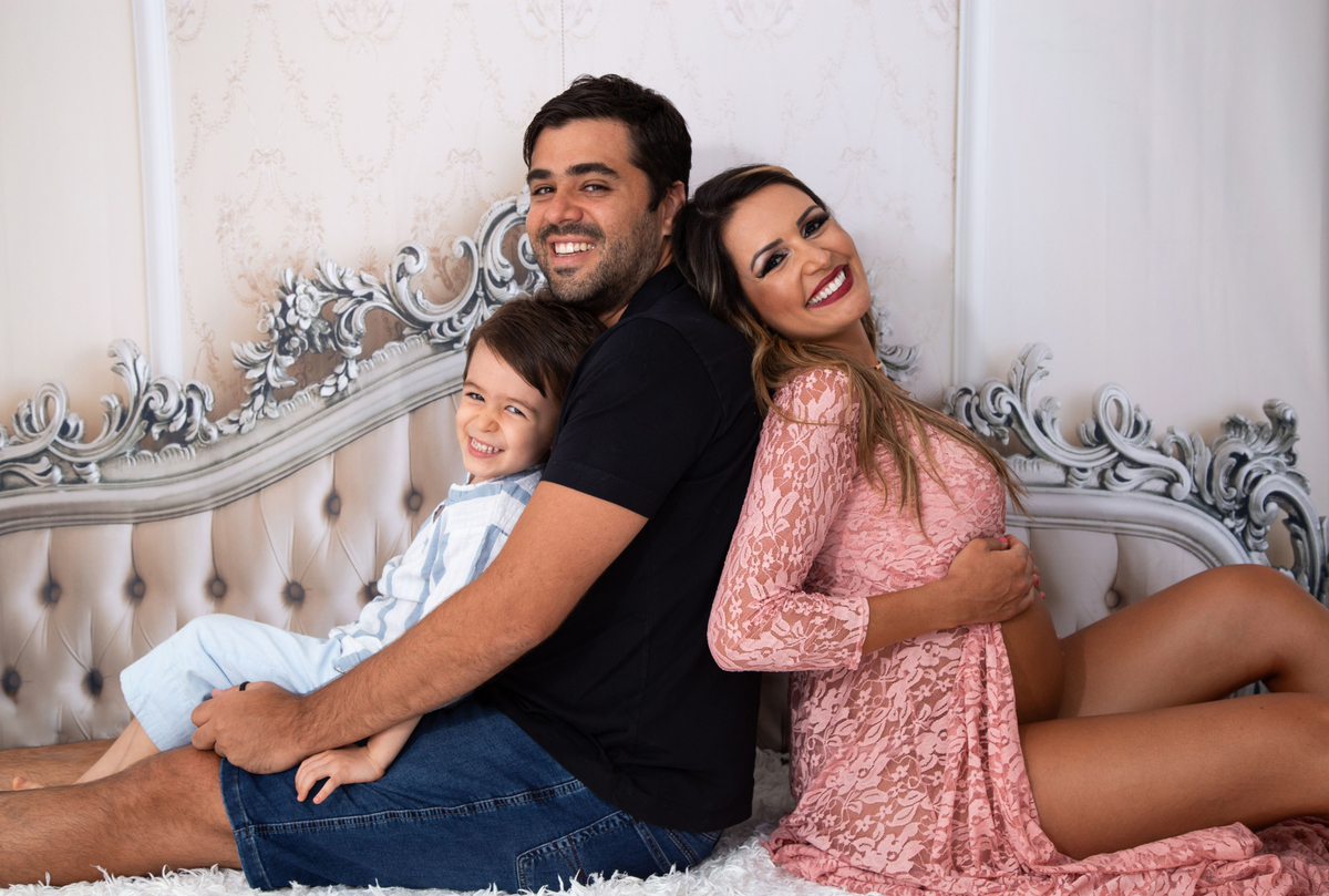 fotografia da família sentados na cama e sorrindo 