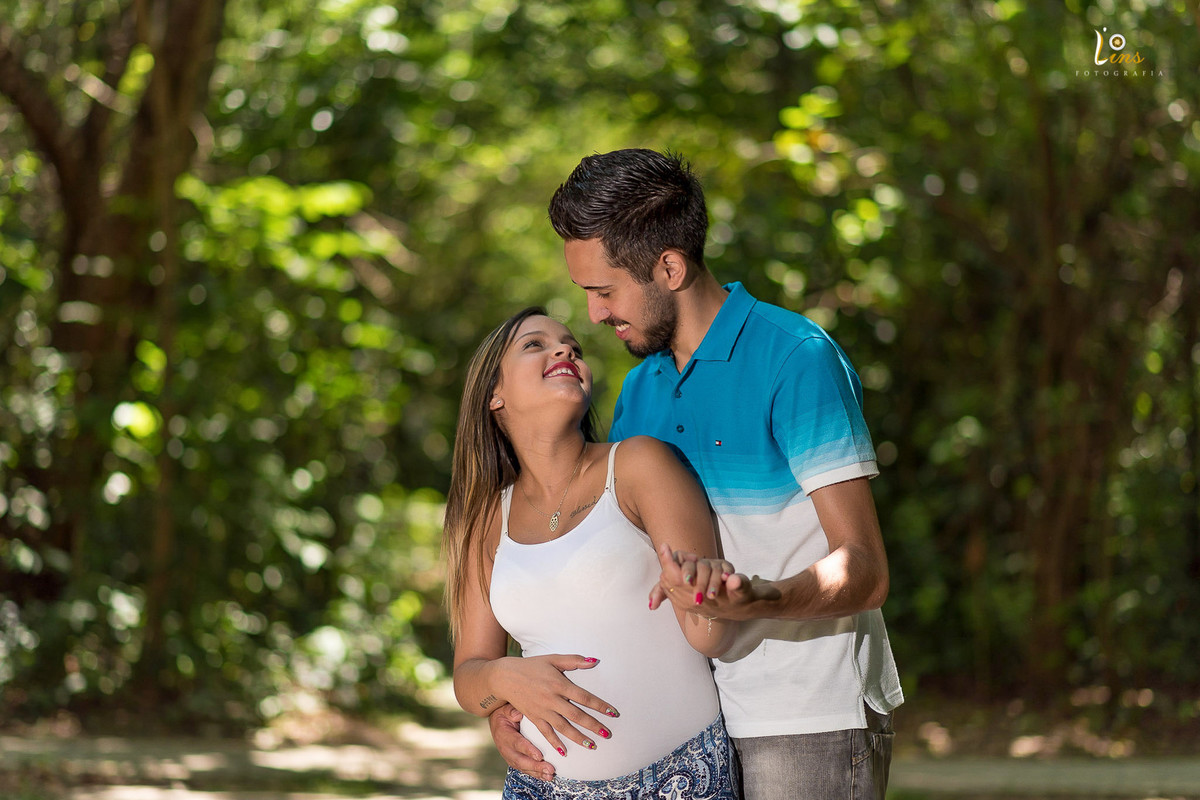 casal de gestante sorrindo e dançando no parque