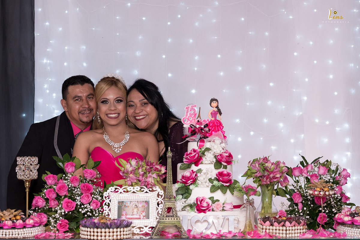 mãe e Pai sorrindo com filha na mesa do bolo
