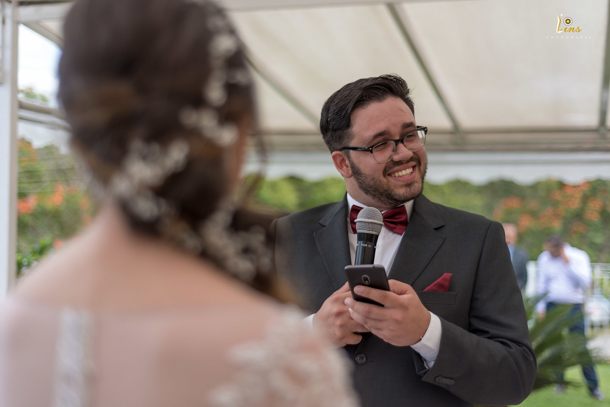 noivo  sorrindo enquanto lê seus votos para noiva na capela 