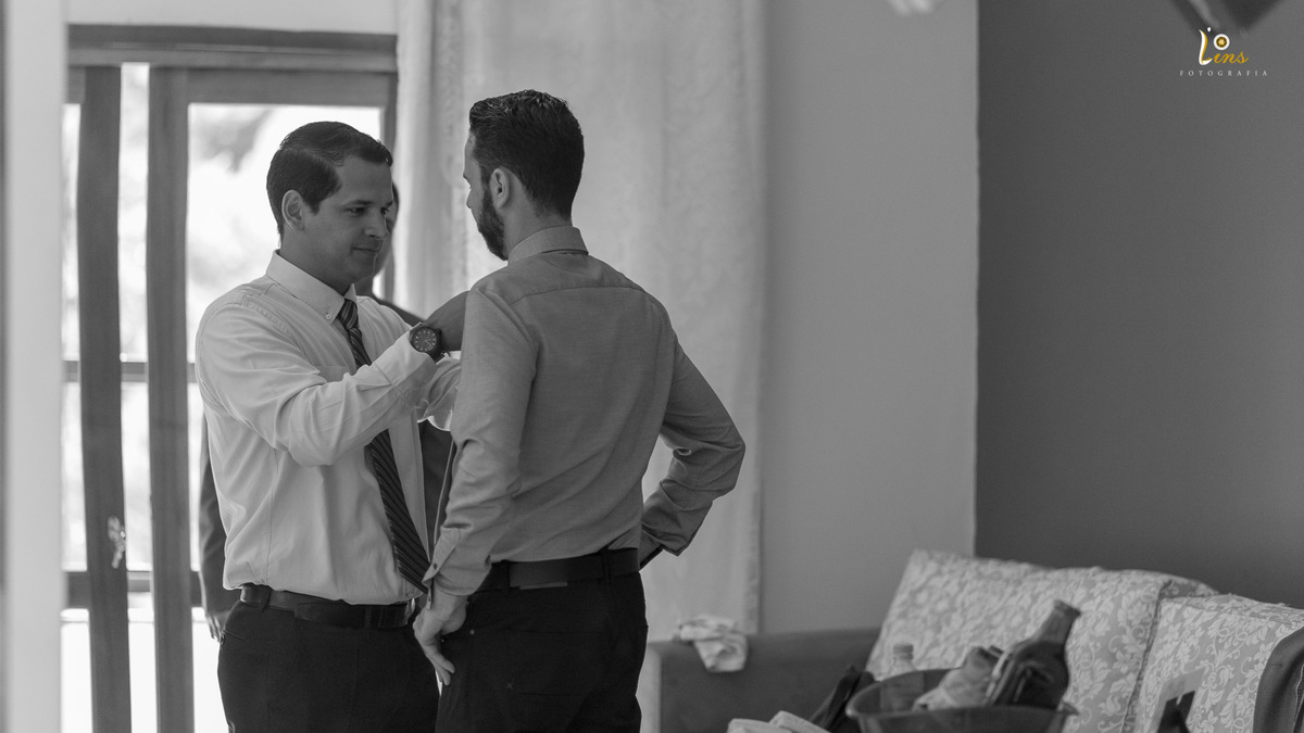 padrinho ajuda noivo com a gravata antes do casamento