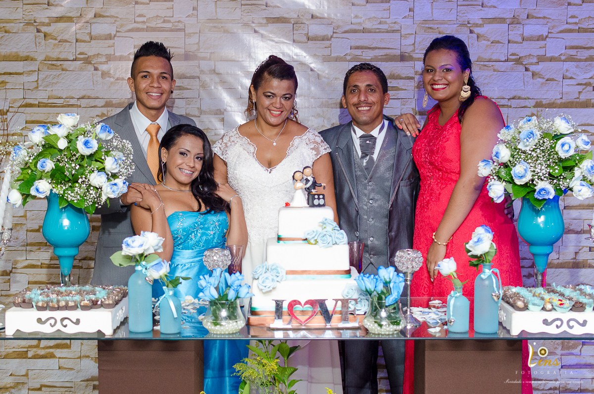fotografia do casal junto a sua família na mesa do bolo
