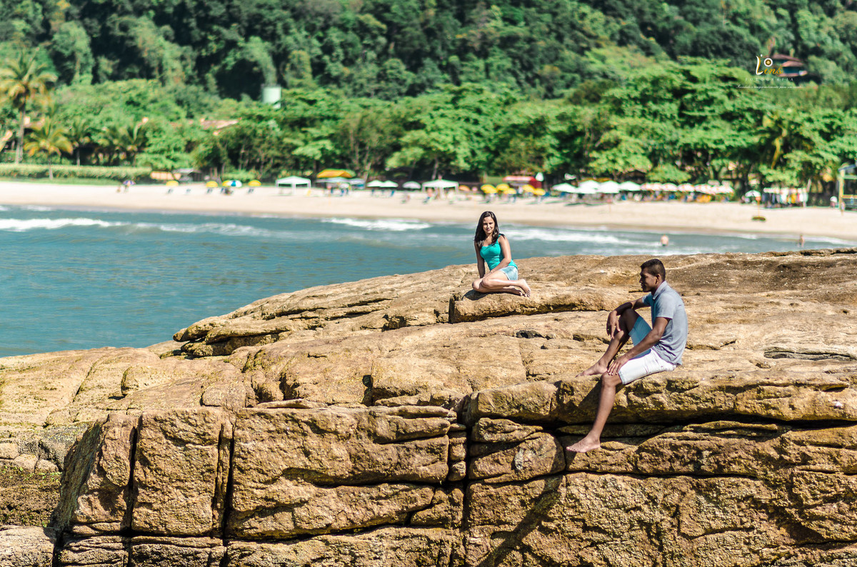 casal sentado na pedra admirando a praia