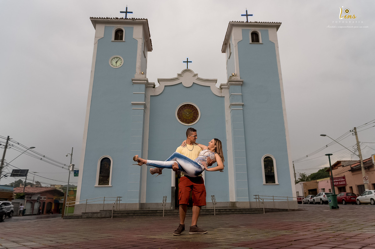 noivo pegando noiva no colo em frente a catedral de guararema