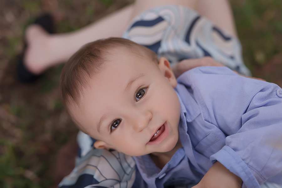 bebe vestido de azul no colo da mãe olhando para cima  em Caxias do Sul