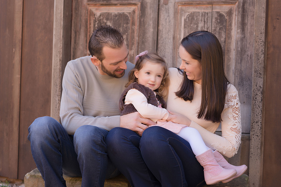 fotografia infantil em caxias do sul; fotografia de família em caxias do sul, pai e mãe segurando filha com roupa rosa no colo