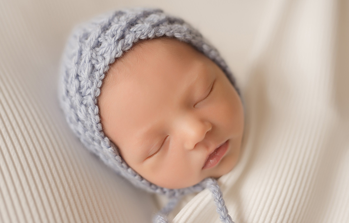 foto newborn em caxias do sul fotografa morgana perini bebe com touca azul rostinho proximo