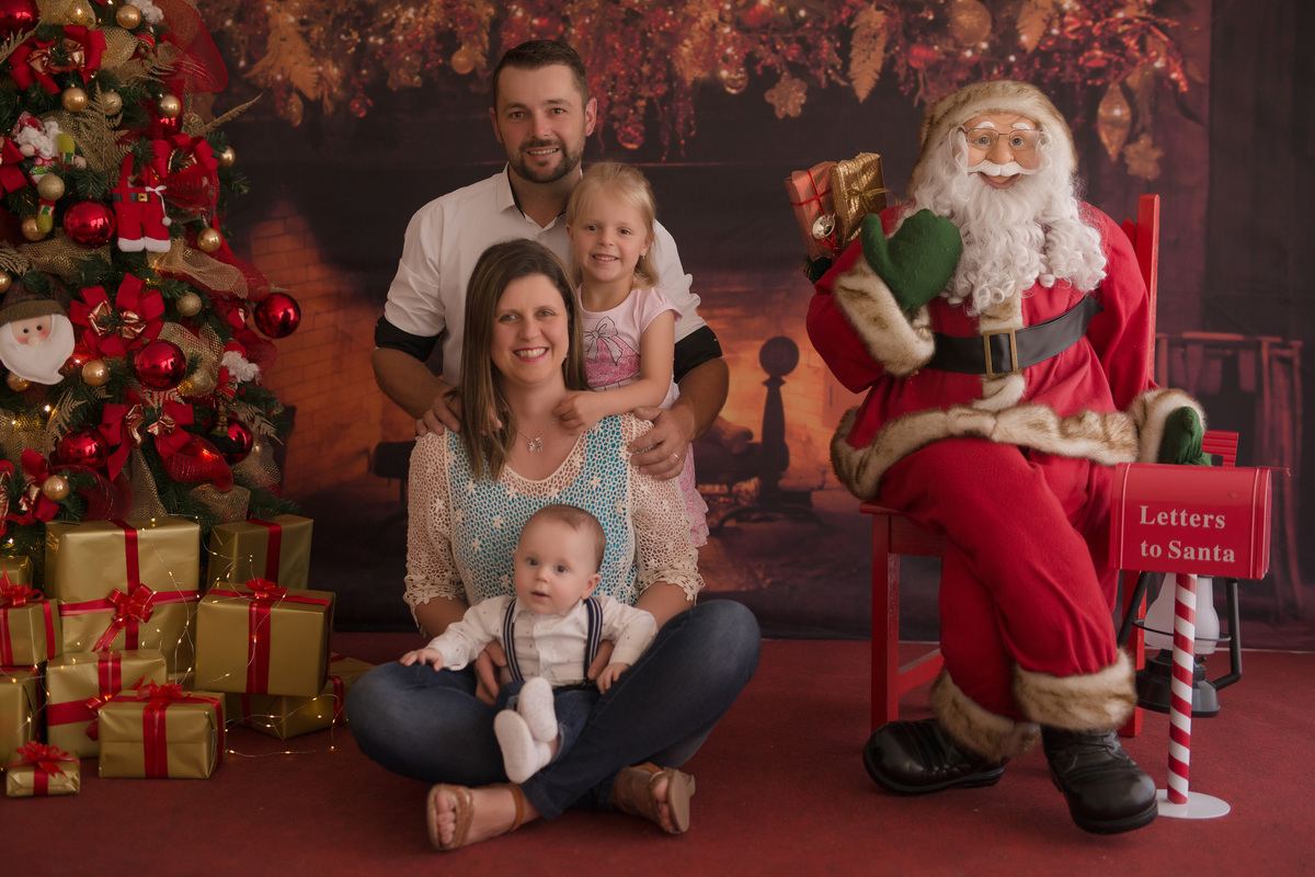 foto de familia em caxias do sul fotografa morgana perini em familia sentada no chão no cenario de natal