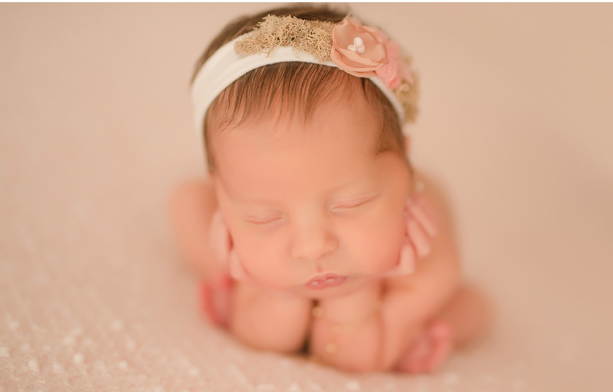 foto newborn em caxias do sul fotografa morgana perini bebe segurando o rostinho com tiara de flores