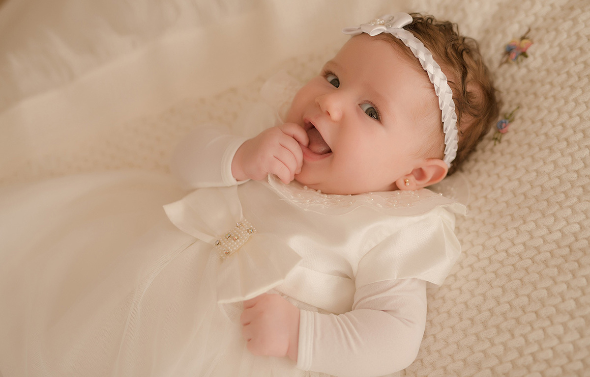 foto de bebe em caxias do sul fotografa morgana perini bebe com a mãozinha na mao e tiara branca