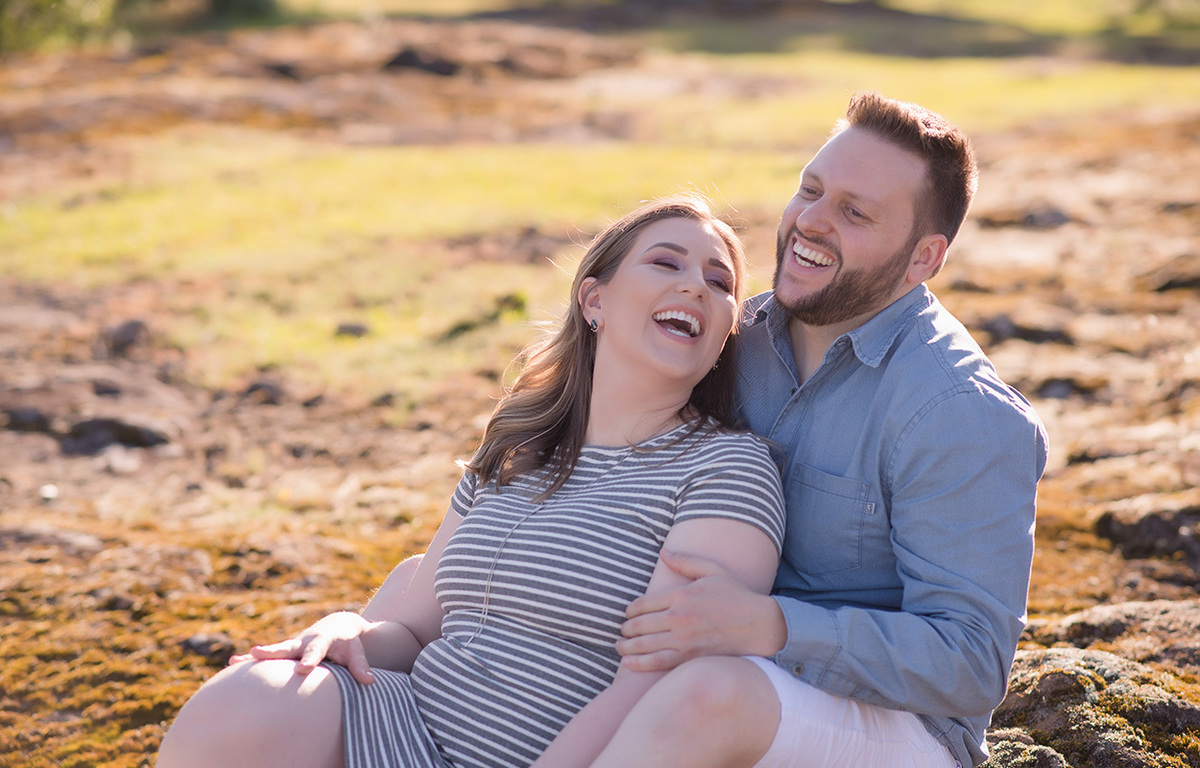 foto de gestante em caxias do sul fotografa Morgana Perini casal sentado nas pedras sorrindo