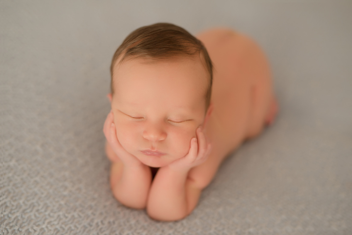 foto newborn em caxias do sul fotografa morgana perini bebe com as mãos no rosto