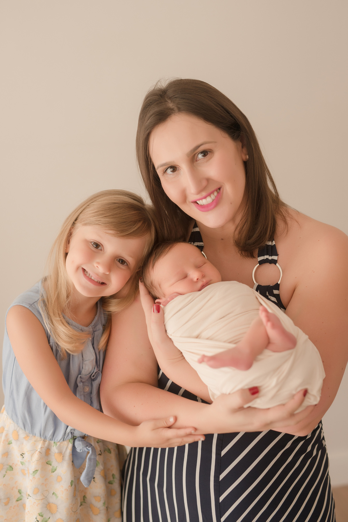 foto newborn em caxias do sul fotografa morgana perini mãe com bebe enrolado em tecido bege e irmazinha