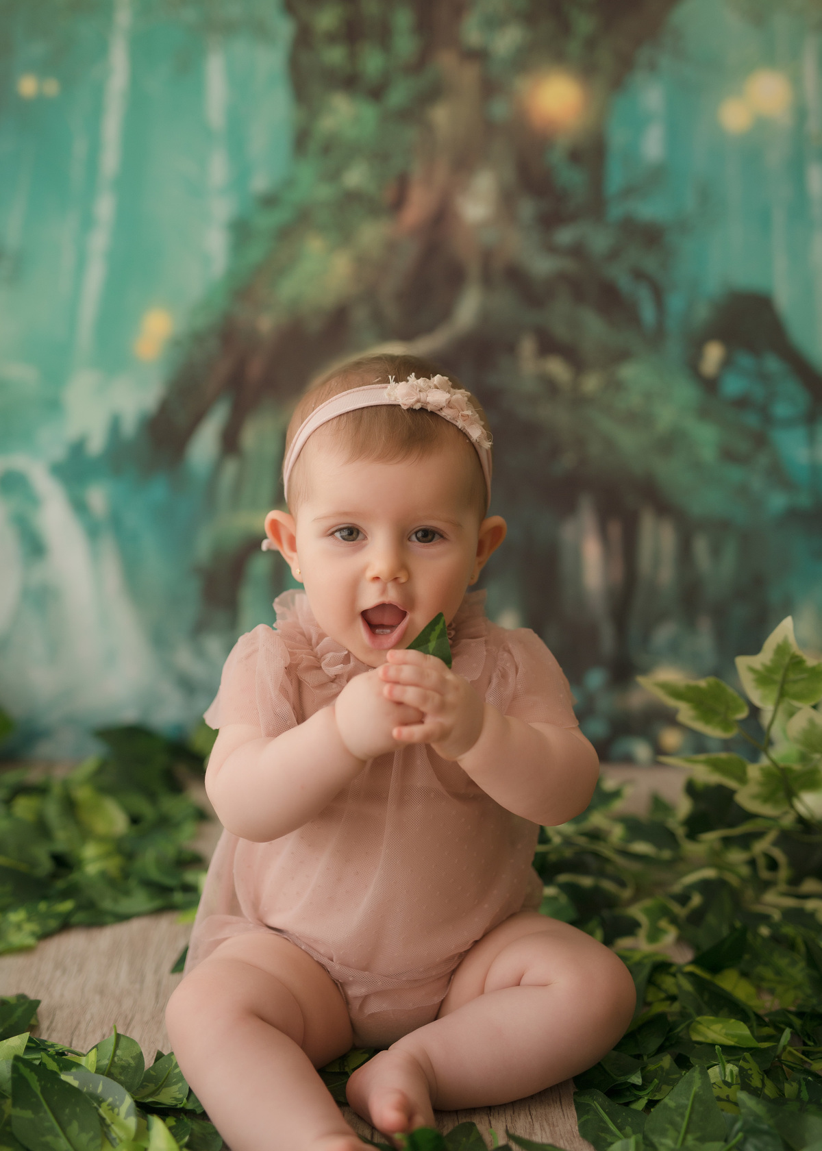 foto de bebe em caxias do sul fotografa morgana perini bebe com tiarinha segurando uma folha na mão