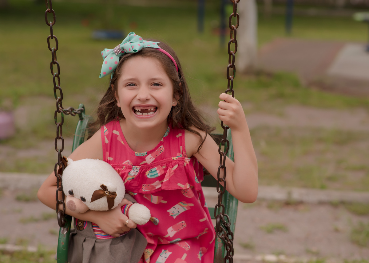 foto de criança em caxias do sul fotografa morgana perini criança andando de balanço com urso