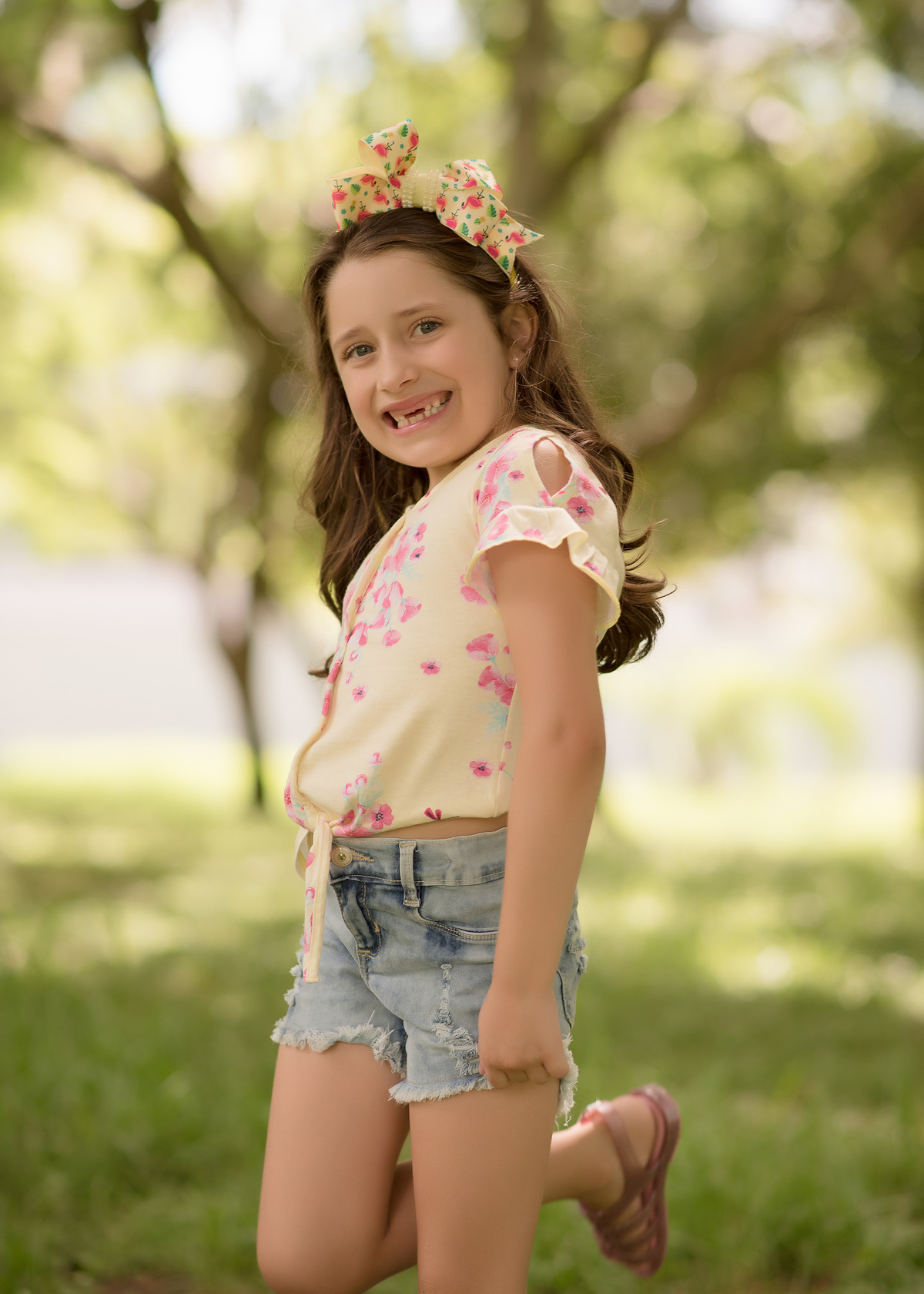 foto de criança em caxias do sul fotografa morgana perini menina sorrindo em fundo de arvores