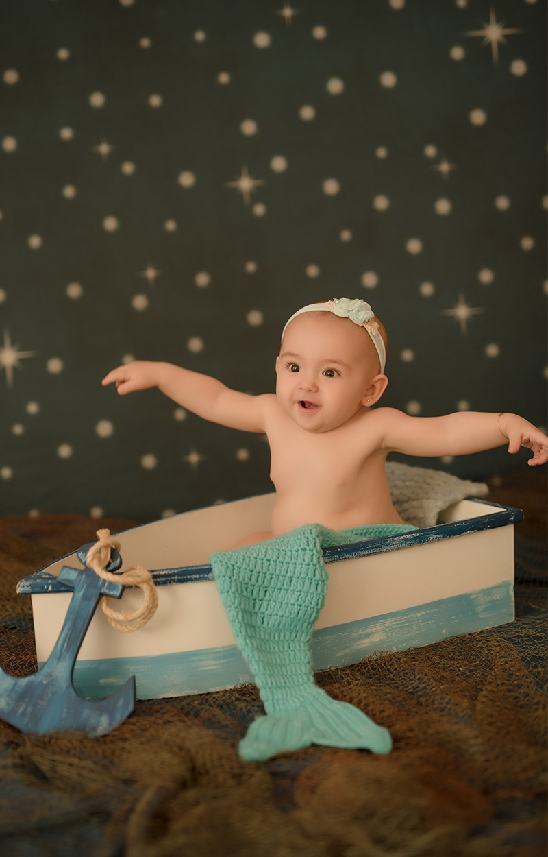 foto de bebe em caxias do sul fotografa morgana perini bebe sentada em barquinho fundo azul