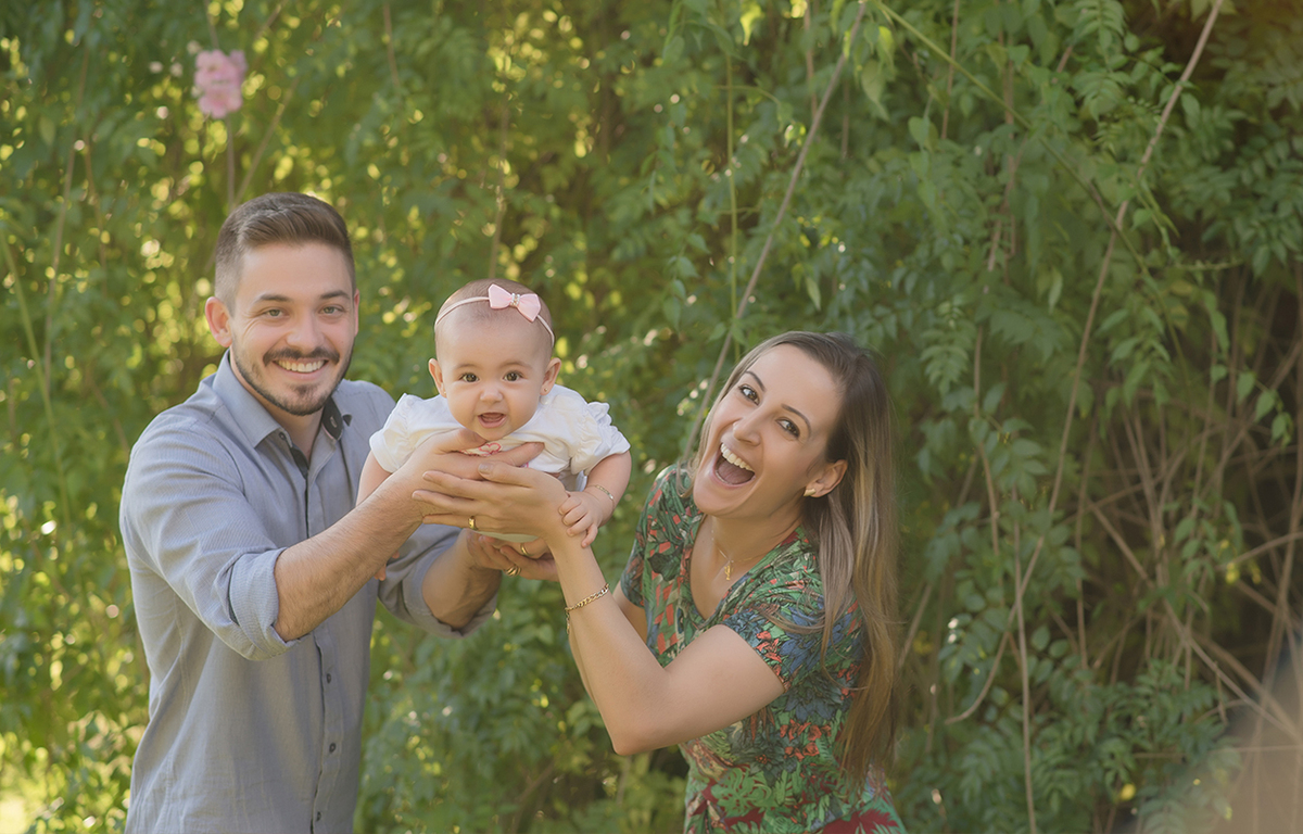foto de bebe em caxias do sul fotografa morgana perini bebe com vestido bege sentada na cadeira bebe brincando com os pais